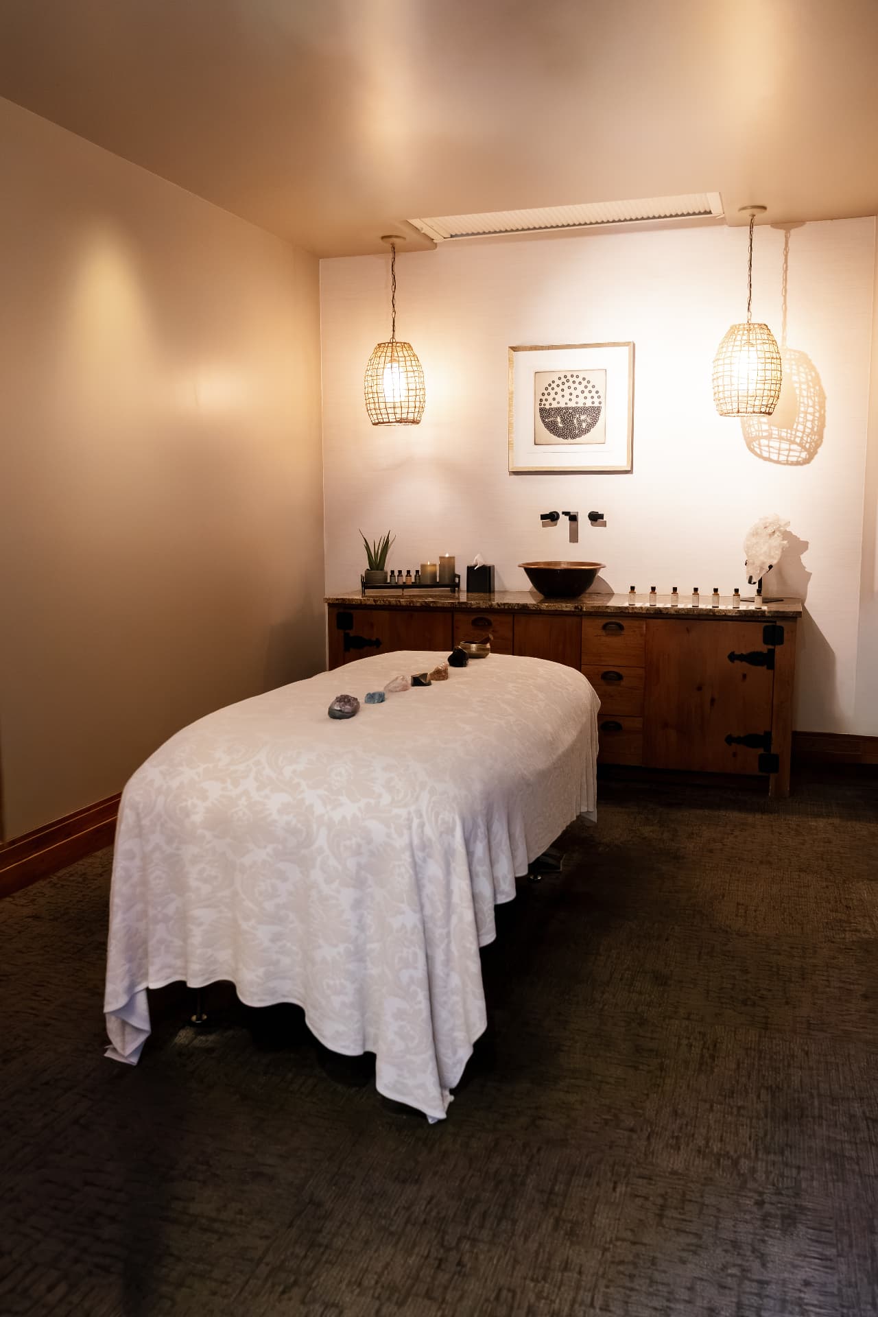Treatment room with massage table, warm pendants and stone accents
