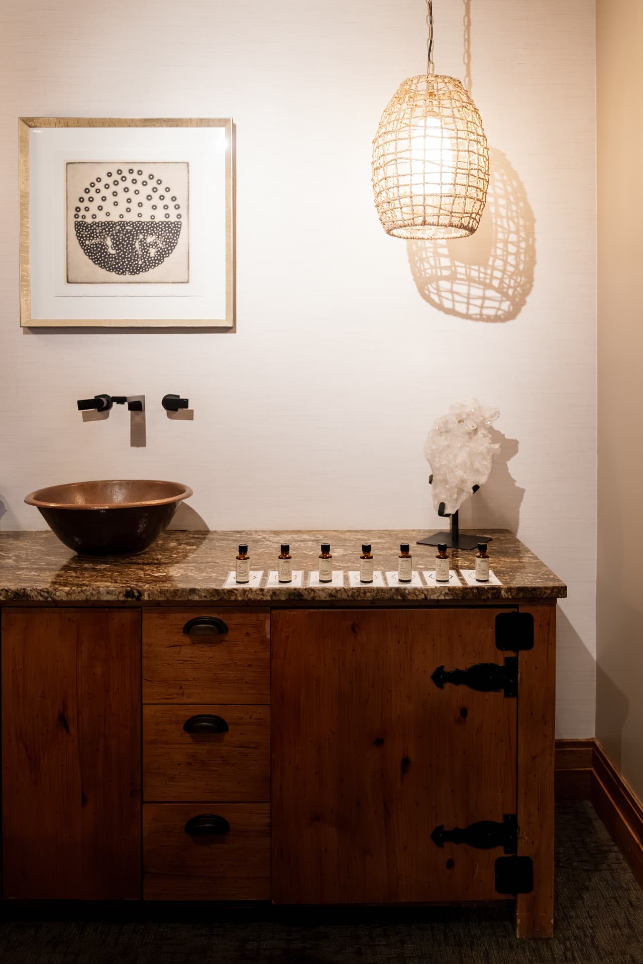 Copper vessel sink and essential oil bottles on a granite vanity